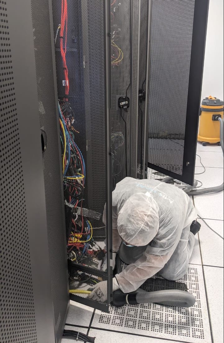 Technician vacuuming server rack during data center cleaning