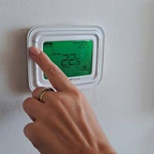 Woman setting AC temperature on thermostat