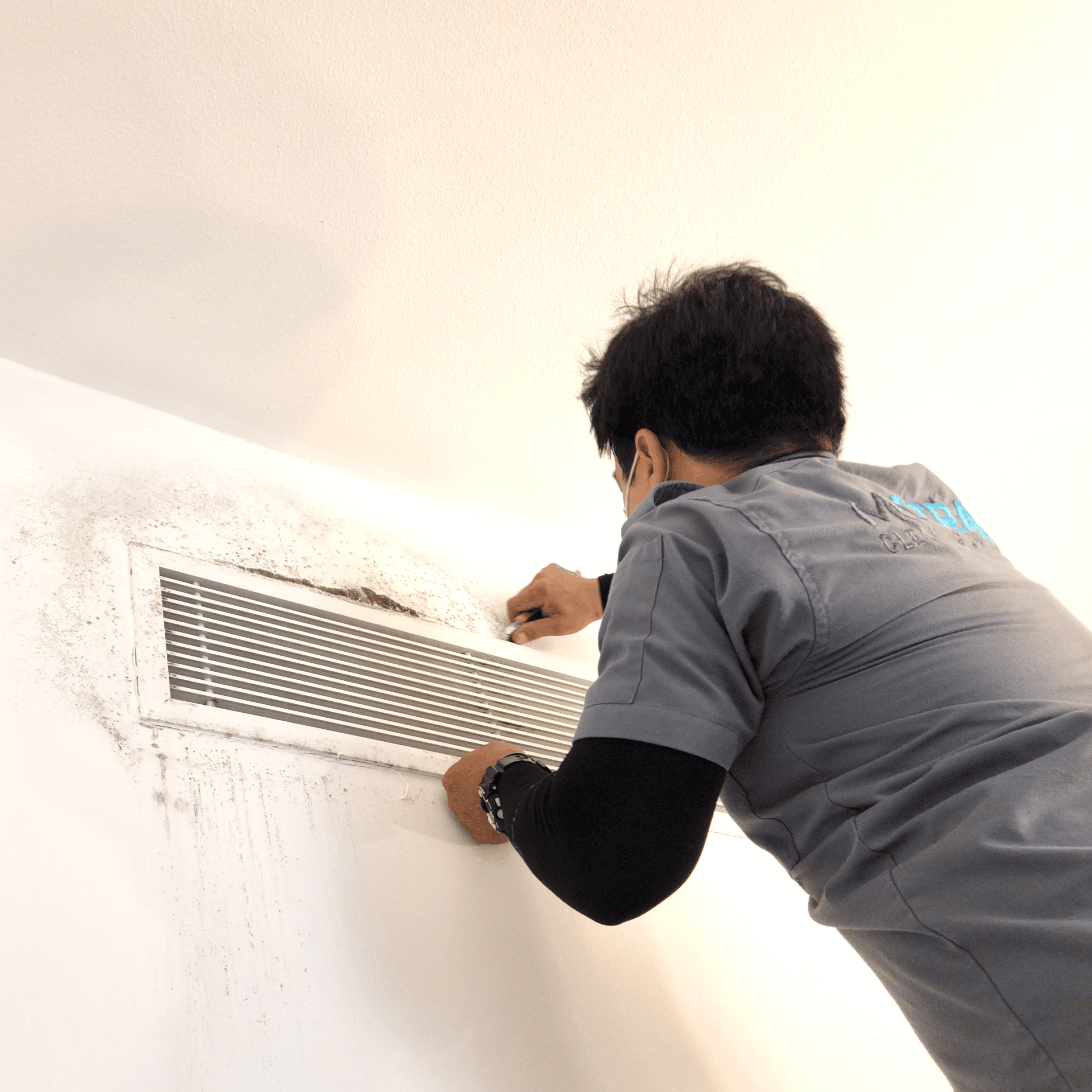 Technician removing an AC Grille before a mold cleaning in the air conditioning system and a mold removal on walls